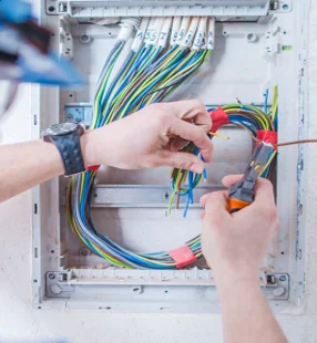 Hands wiring an electrical distribution board